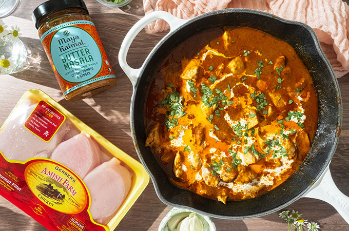 Pan of butter chicken and a jar of Maya Kaimal Butter Masala, and a package of Gerber's Chicken