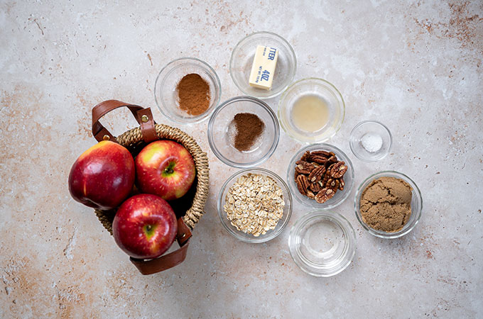 Flat lay with a basket of apples, and the rest of the ingredients for these baked autumn oatmeal apples