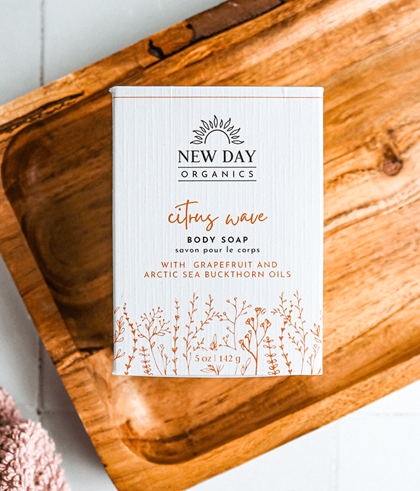 A Box of New Day Organics Citrus Wave Body Soap on a Wood Board