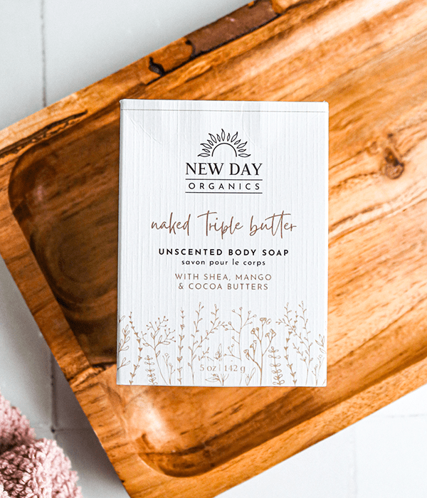 A Box of New Day Organics Naked Triple Butter Unscented Body Soap on a Wood Board